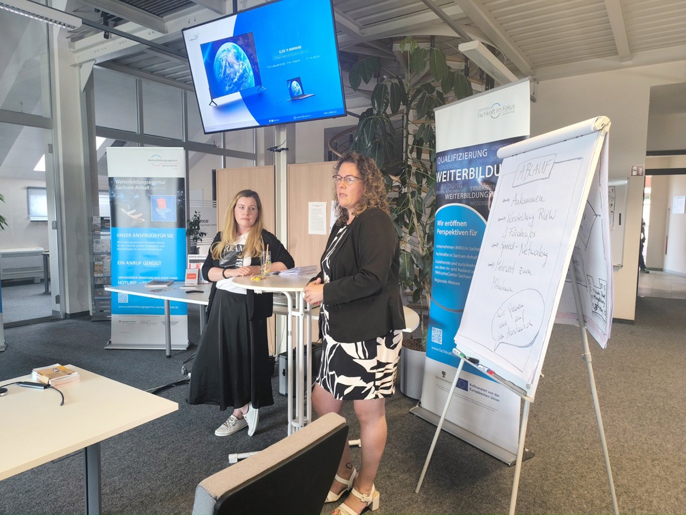 2 Beraterinnen an einem Stehtisch folgen der Diskussion