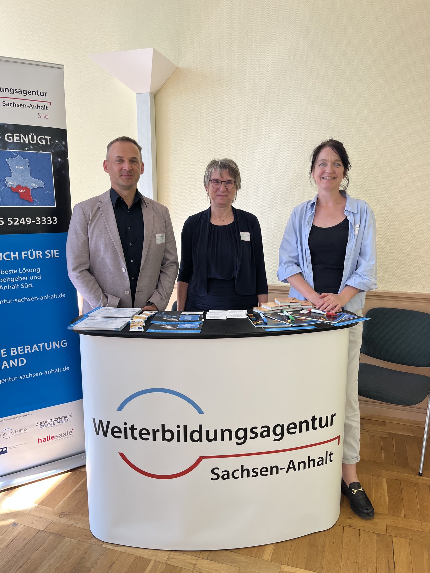 3 Personen hinter dem Counter der Weiterbildungsagentur Sachsen-Anhalt.